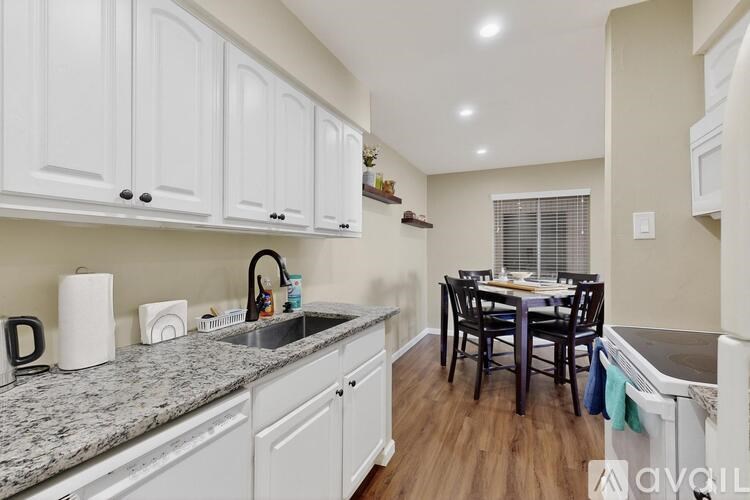 A kitchen with white cabinets and a granite countertop.