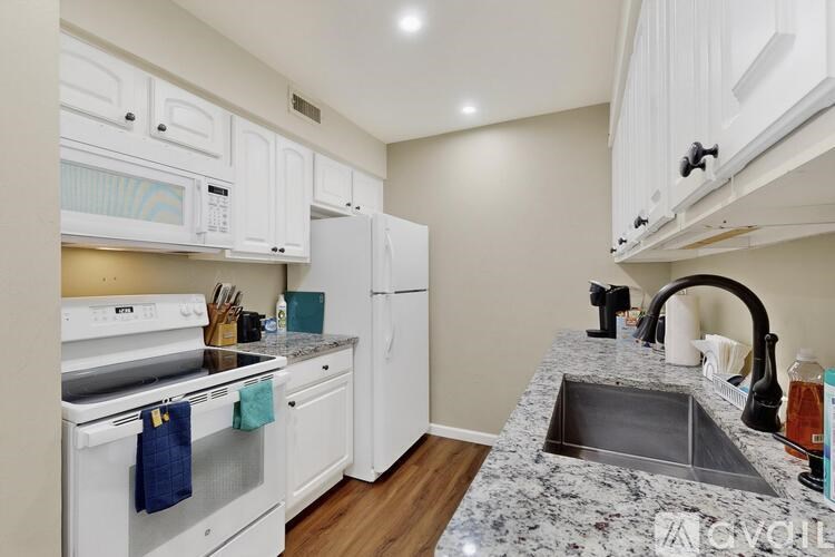 A kitchen with white appliances and a granite countertop.