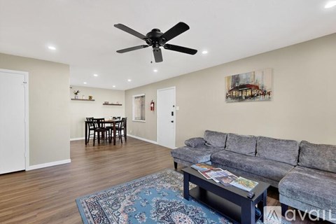 A living room with a grey couch and a ceiling fan.