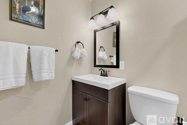 A bathroom with a white sink, brown cabinet, and a white bathtub.