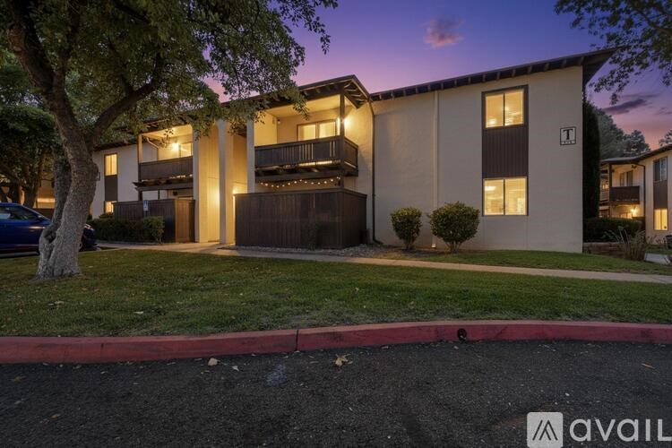 A building with a balcony and a tree in front of it.
