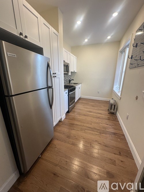 A kitchen with a stainless steel refrigerator and wooden floors.