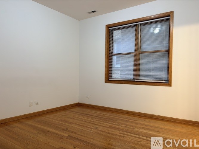 A room with a wooden floor and a window with blinds.