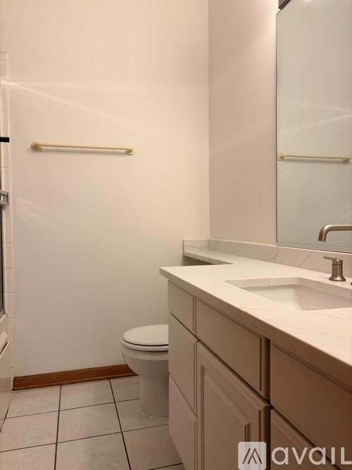 A bathroom with a toilet, sink and mirror.