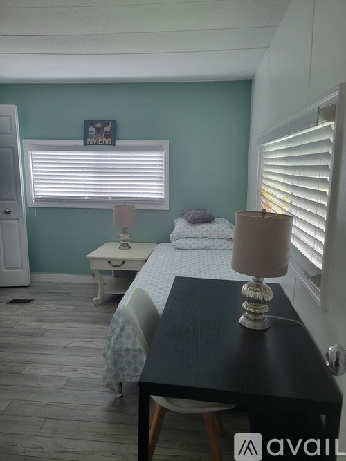 A bedroom with a bed, nightstand, and window with blinds.
