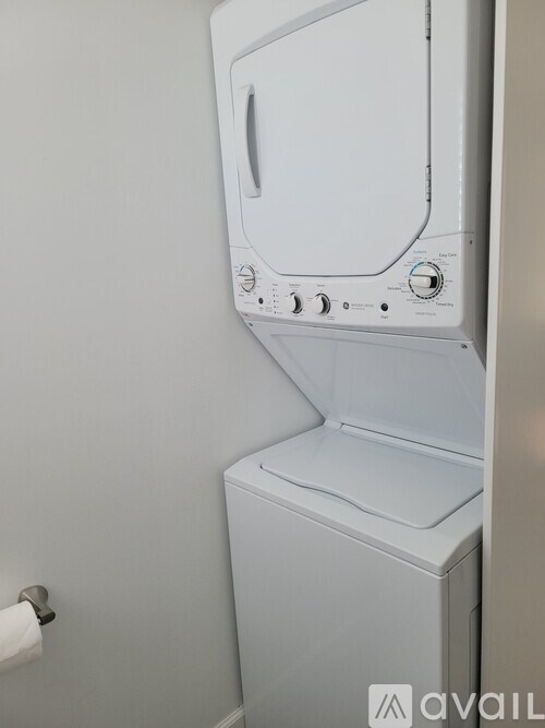 A white dryer is sitting in a bathroom next to a towel rack.