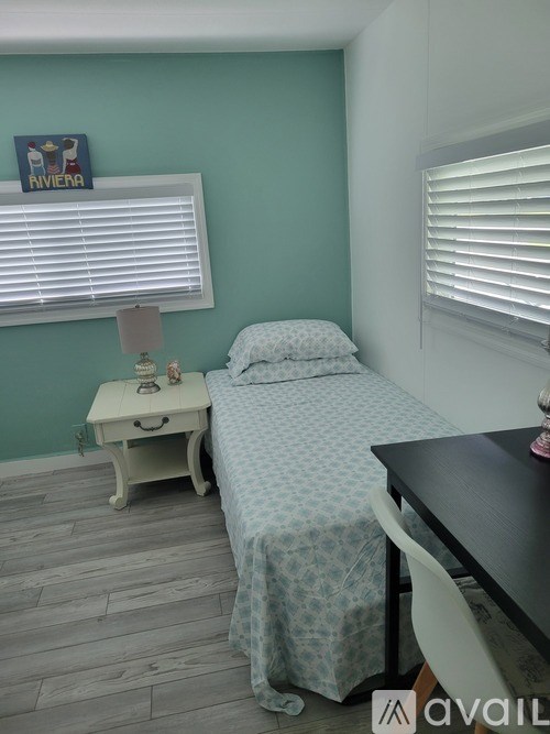 A bedroom with a bed, nightstand, and window with blinds.