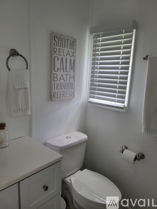 A bathroom with a toilet, sink, and a sign that says "soothe relax calm bath tranquil refresh".