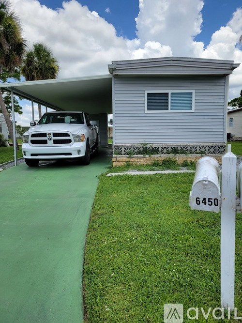 A white truck is parked in front of a grey house.