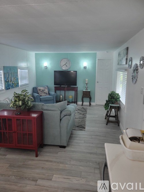 A living room with a grey couch, a red cabinet, and a television.