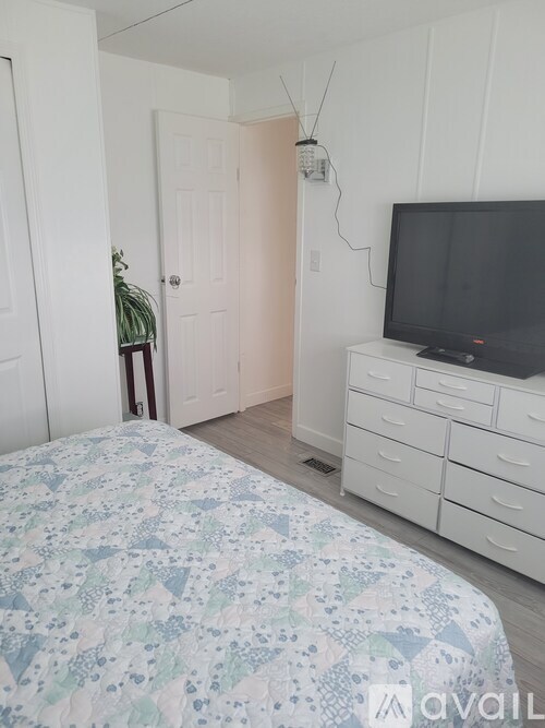 A bedroom with a bed, dresser, and television.