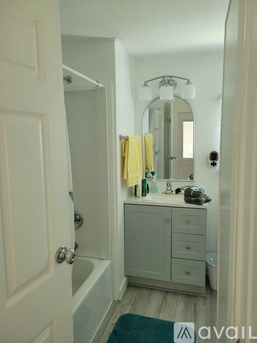 A bathroom with a white door, a white cabinet, a mirror, and a yellow towel.