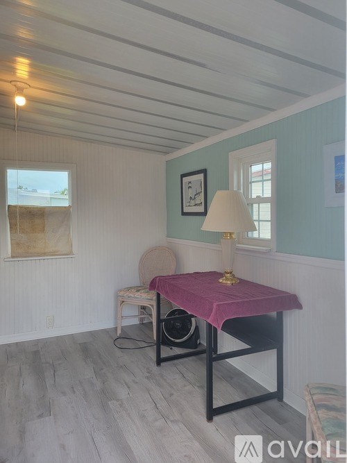 A room with a chair and a table with a lamp on it.