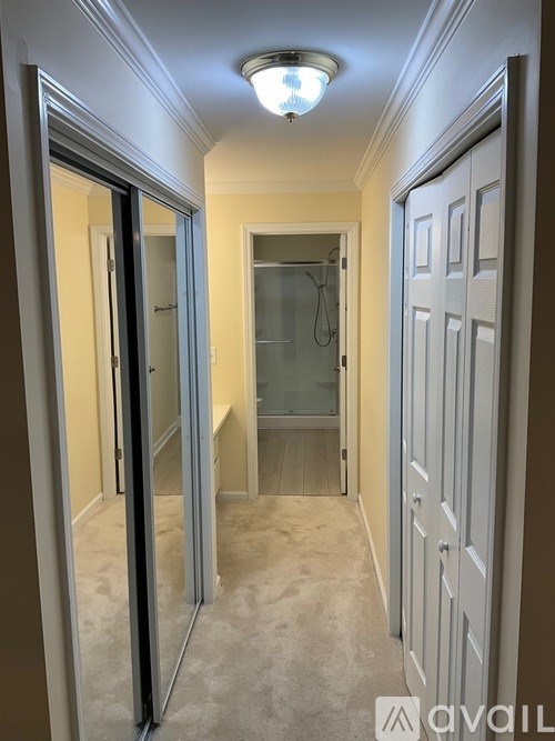 A hallway with a glass door and a white door.