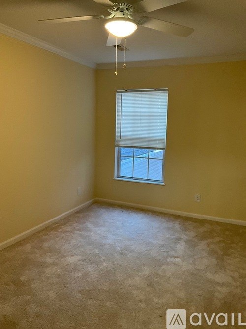 A room with a ceiling fan and a window with blinds.