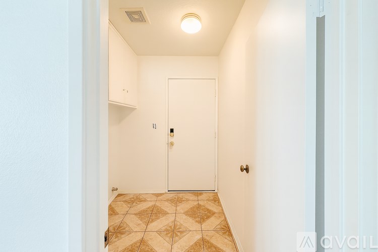 A hallway with a white door and tiled floor.