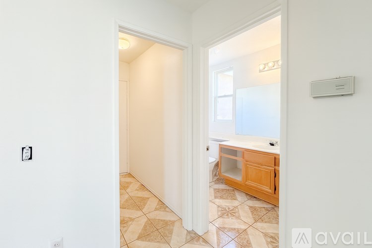 A hallway with a tiled floor and a doorway leading to another room.