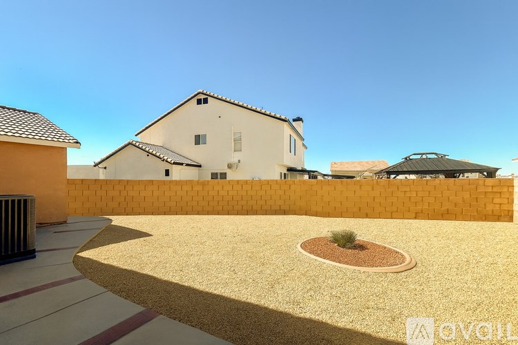 A house with a white exterior and a brown roof is surrounded by a yellow wall.