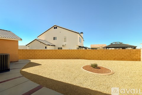 A house with a white exterior and a brown roof is surrounded by a yellow wall.