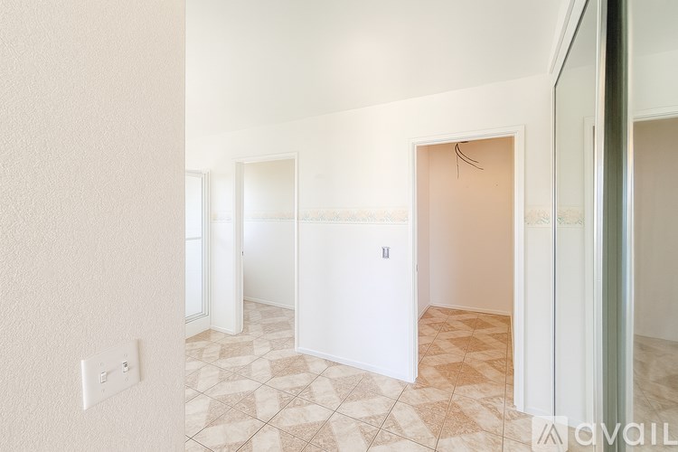 A hallway with a tiled floor and white walls.