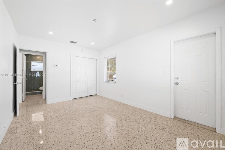 A spacious room with white doors and a marble floor.