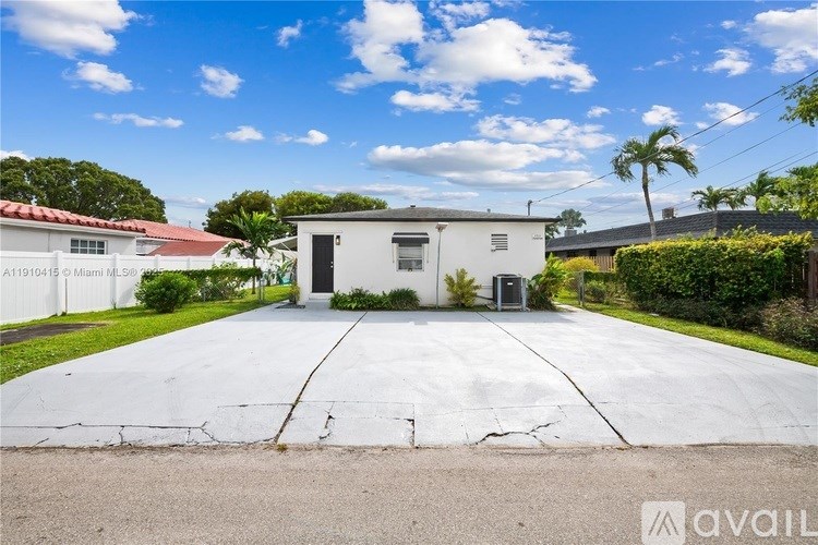 A house with a white fence and a driveway in front of it.