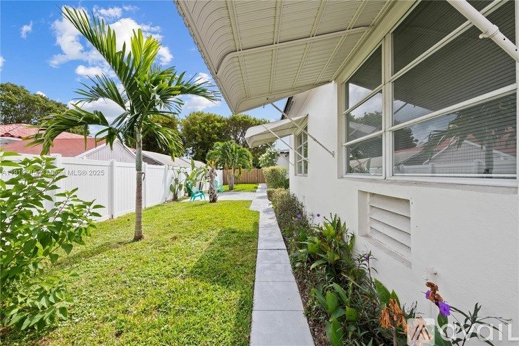 A white house with a green lawn and a tree in front.