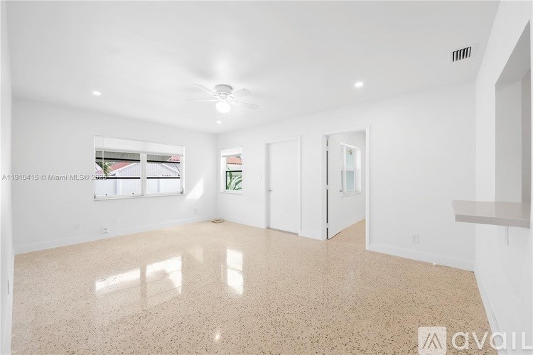 A spacious room with a large window, a door, and a wall-mounted shelf.