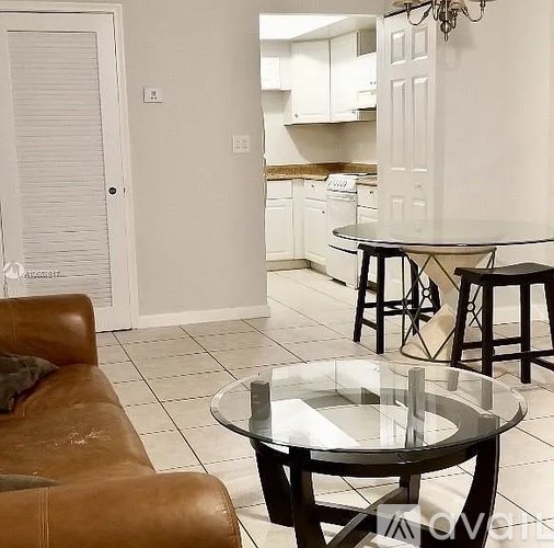 A living room with a brown leather couch and a glass table.