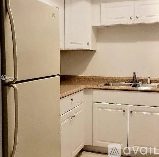 A kitchen with a refrigerator, cabinets, and a countertop.