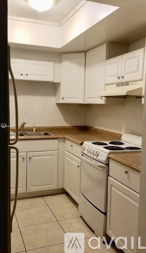 A kitchen with white cabinets and a white stove.
