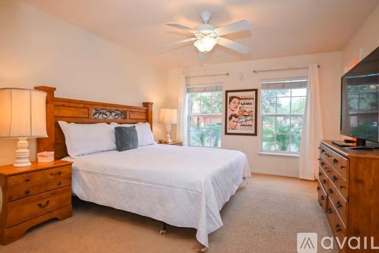 A bedroom with a bed, dresser, and a ceiling fan.