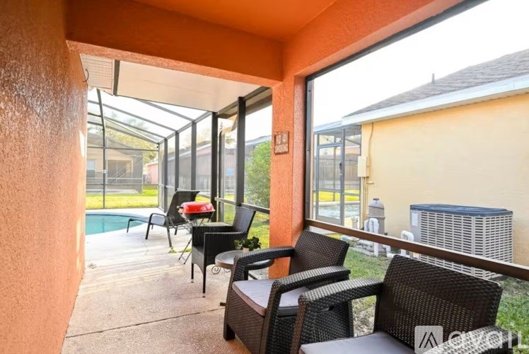 A patio with a table and chairs overlooking a pool.