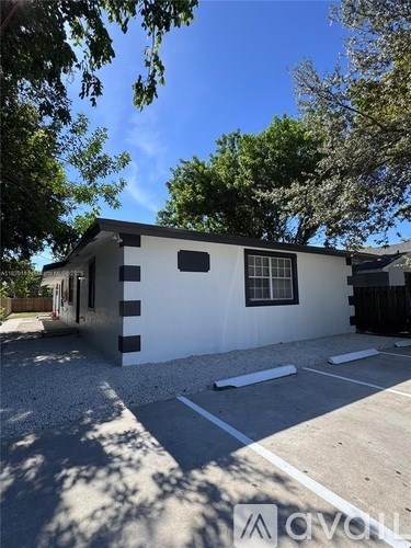 A white house with a black fence and a gravel driveway.