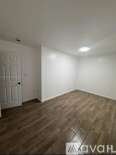 A room with wooden flooring and a white door.