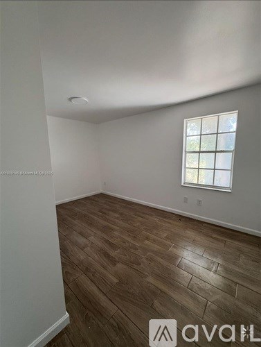 A room with wooden flooring and a window.