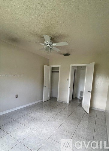 A room with a ceiling fan and tile flooring.