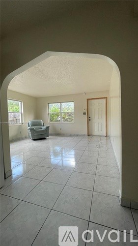 A spacious room with a grey tiled floor and a white sofa.
