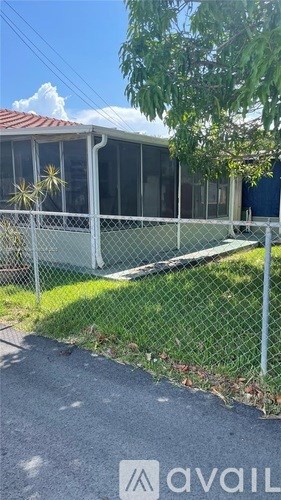 A house with a fence and a tree in front.
