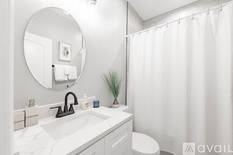 A bathroom with a white sink, toilet, and shower curtain.