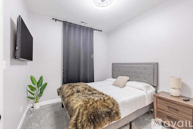 A bedroom with a bed, a television, and a plant.