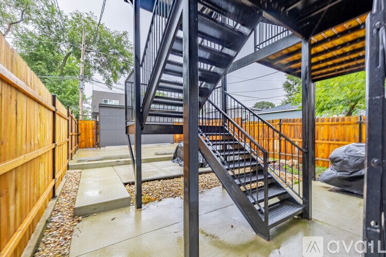 A black metal staircase with a wooden railing.