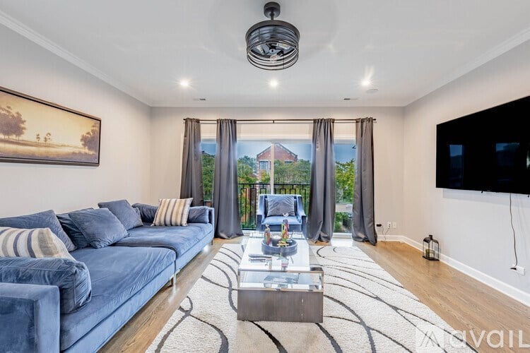 A living room with a blue couch and a television on the wall.