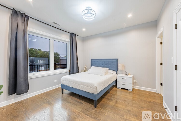 A bedroom with a large bed and a window with curtains.