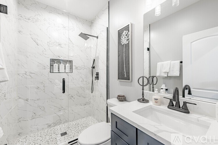 A bathroom with a marble tile shower and a white toilet.