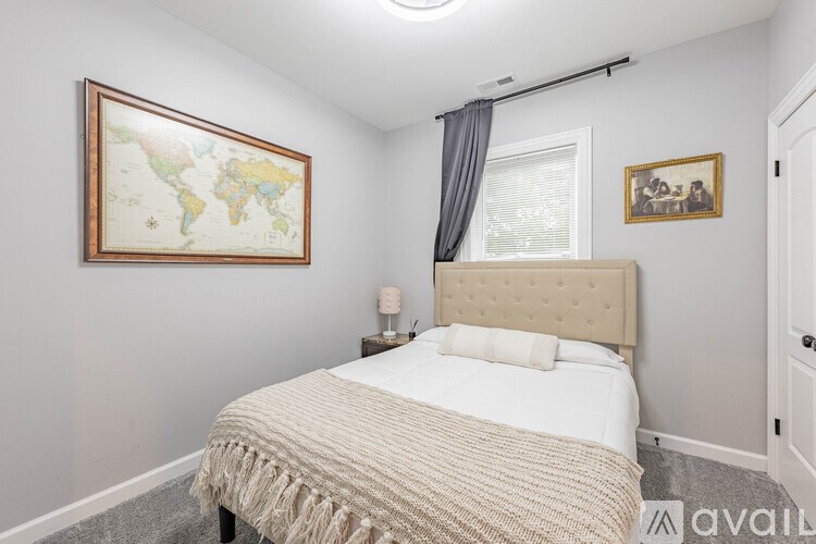 A bedroom with a bed, a lamp, a window, and a world map on the wall.