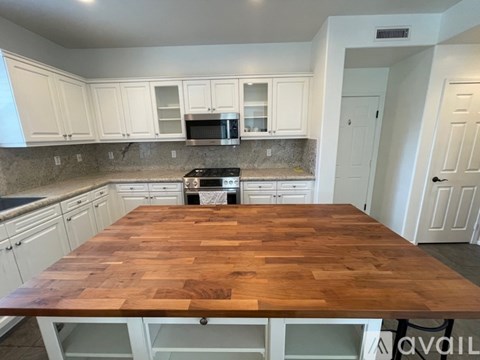 A kitchen with a wooden table in the middle.