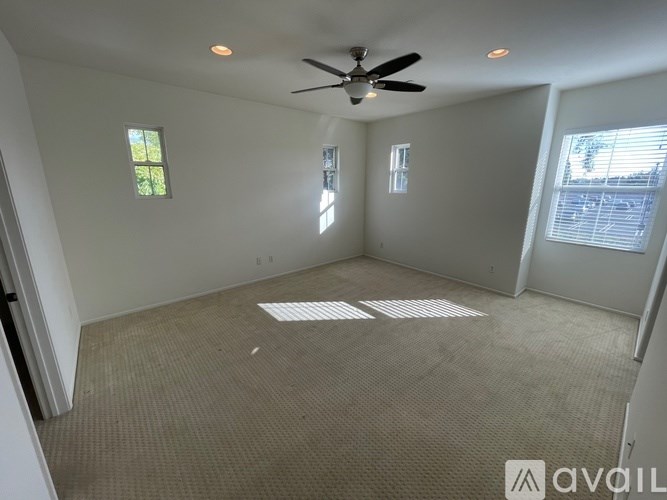 A room with a ceiling fan and two windows.