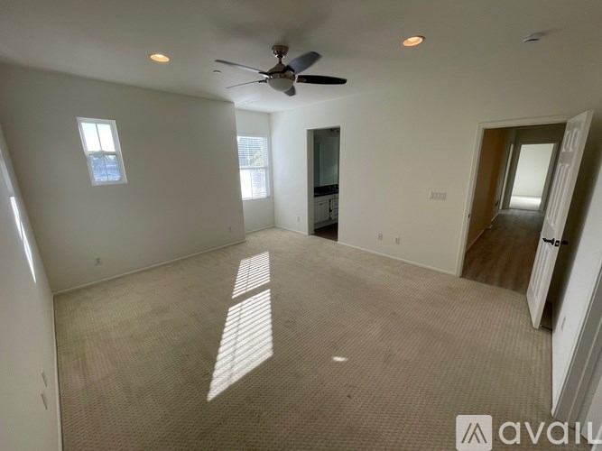 A spacious room with a ceiling fan and a door leading to another room.
