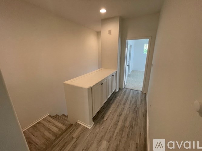A room with a white cabinet and wooden flooring.